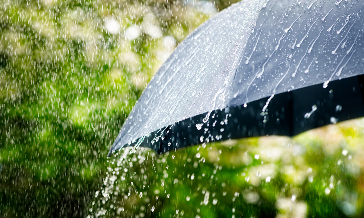 Ergiebiger Regen prasselt auf einen dunklen Regenschirm nieder